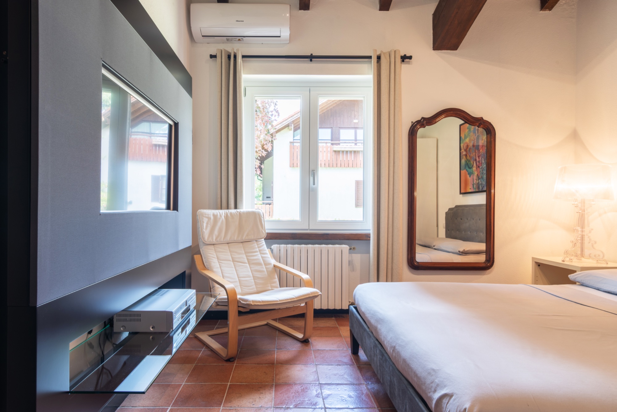 The gray bedroom — TV, reading chair, glimpse of bed