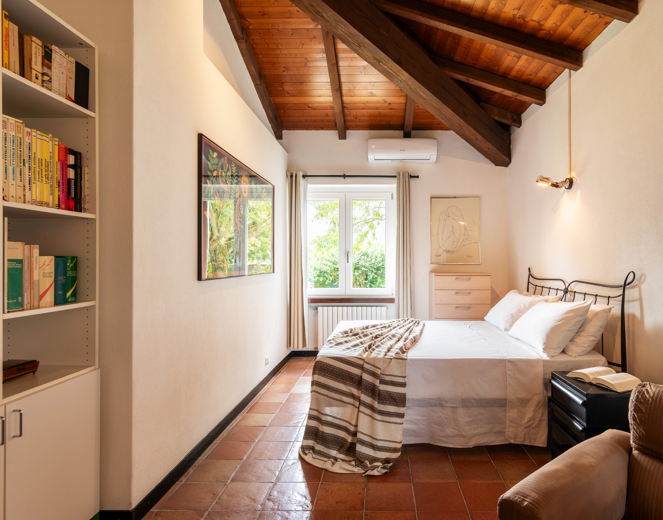 The iron bed — books on the wall, a reading chair