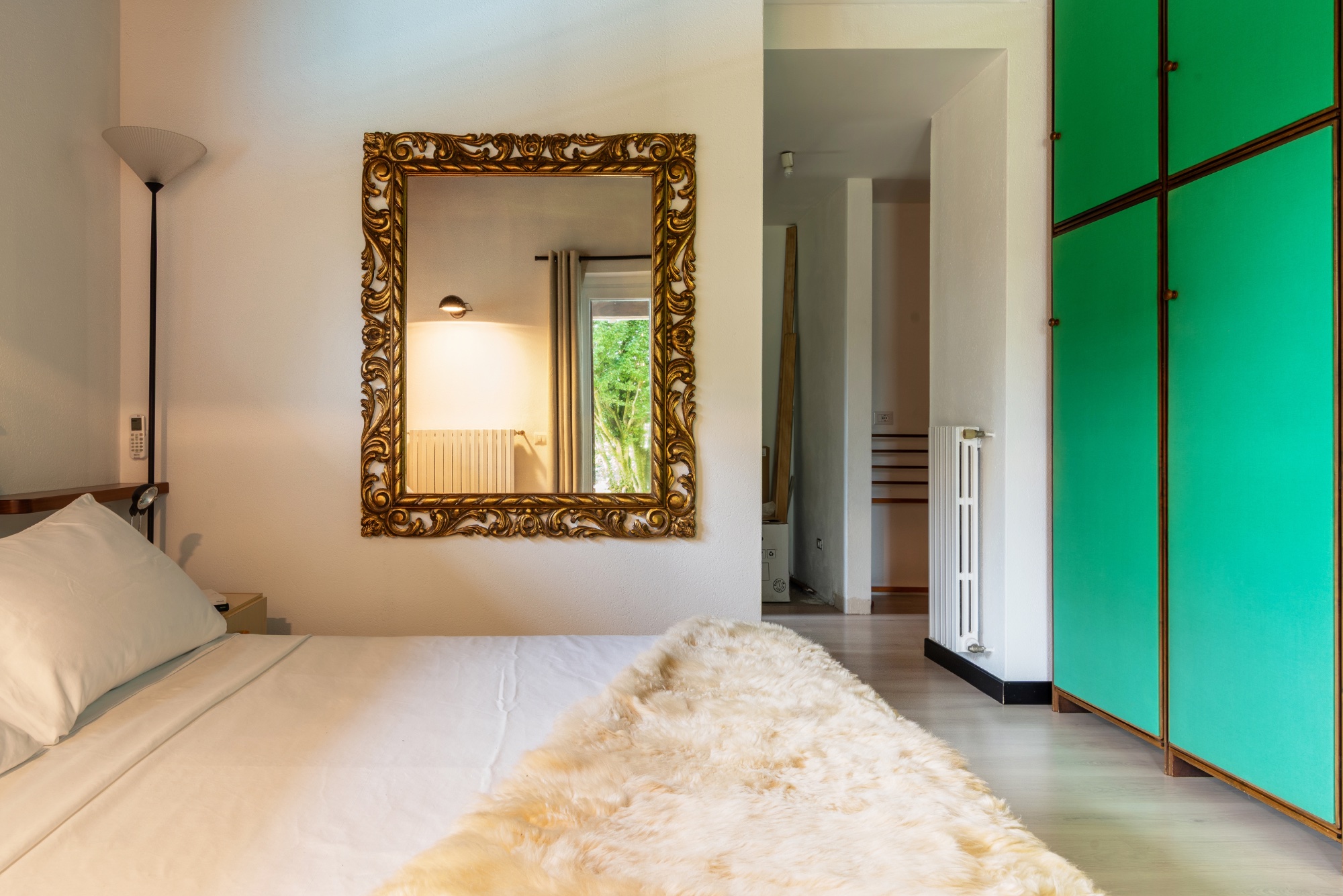 The gold mirror — bed and green wardrobe edge