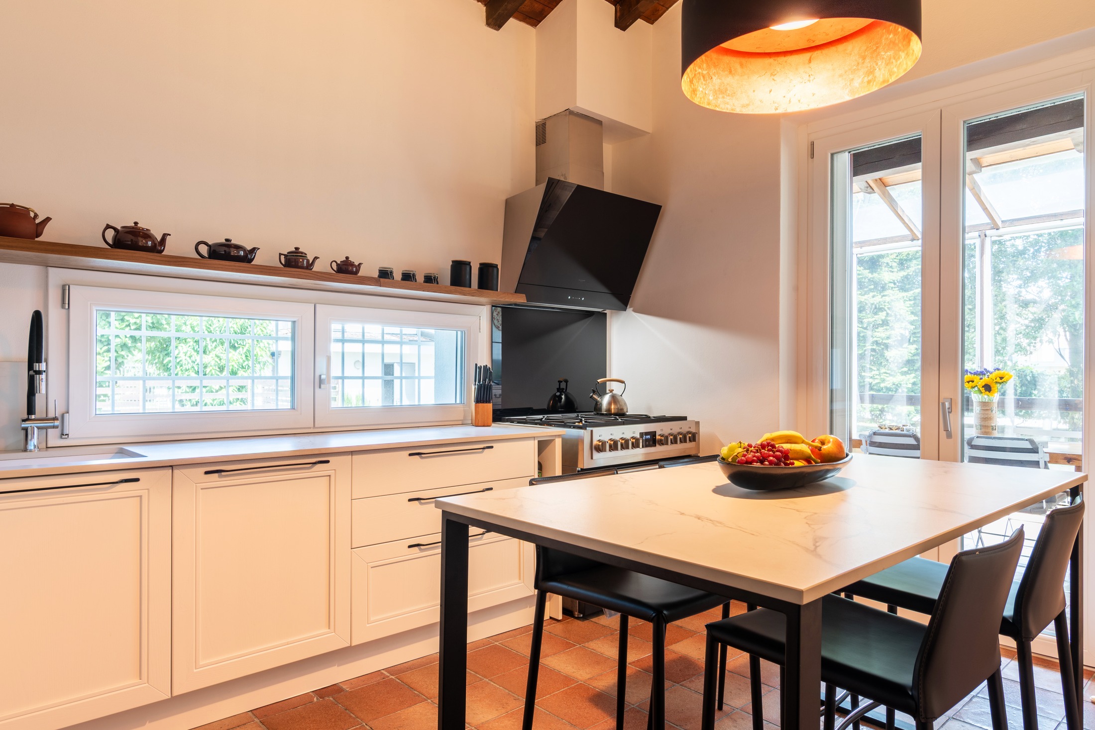 The kitchen — marble table, gas range, French doors to the winter garden